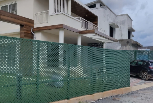 Green PVC lattice fence installed around a modern residential building, providing privacy and aesthetic appeal.